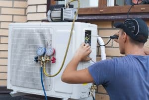 the worker installs the outdoor unit of the air conditioner on the wall of the house