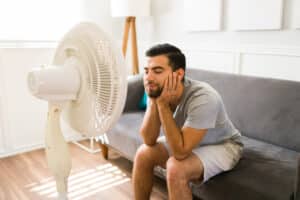 man relaxing in front of electric fan